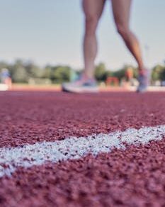 Closeup view of athlete's legs standing on outdoor track, perfect for sports-related themes.