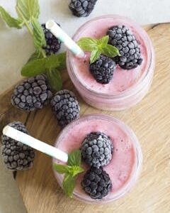 Enjoy a refreshing blackberry smoothie topped with fresh mint leaves, perfect for a summer treat.